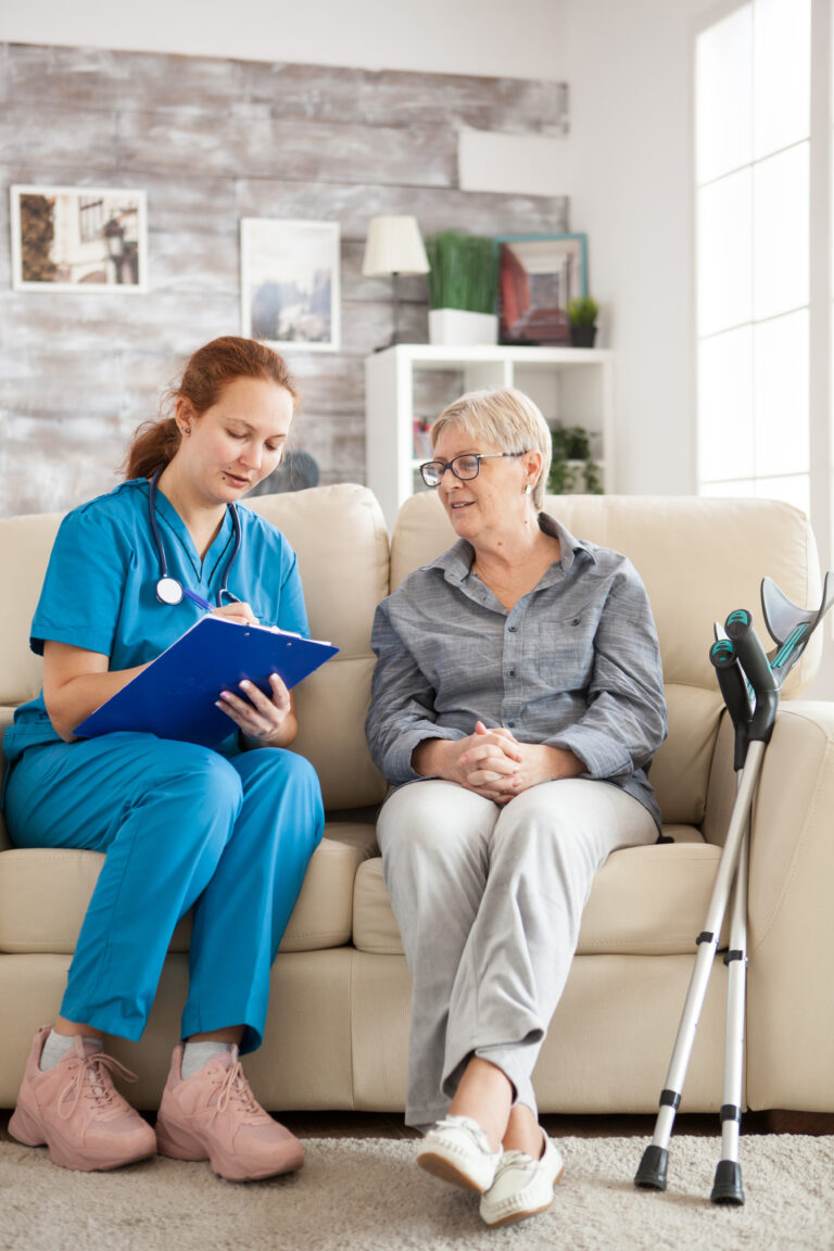 female doctor with senior woman sitting on couch